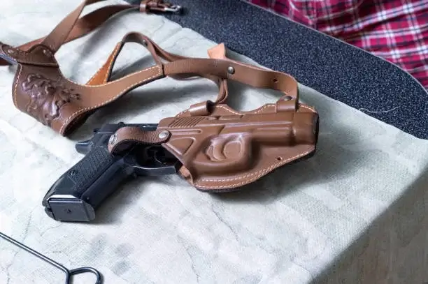 Eine Pistole in einem Lederholster. Die Pistole liegt auf dem Tisch.