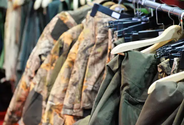Стеллаж с военной одеждой, включая камуфляжные куртки, висит на витрине.