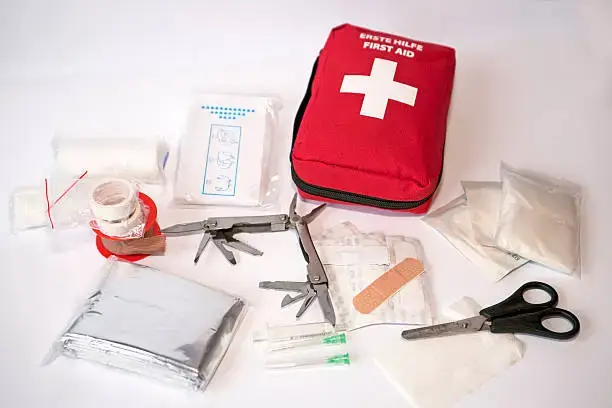 Open first aid kit with bandages, scissors, triangle scarf, syringe, plaster, knife, tools, gauze, etc