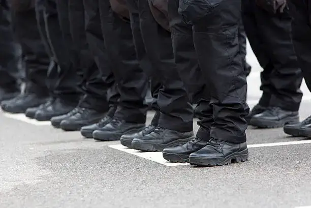 Policemen's black uniforms and boots in line.