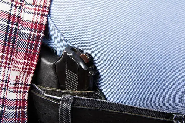 gun concealed carried inside the waistband of a pair of black jeans and a red plaid flannel shirt