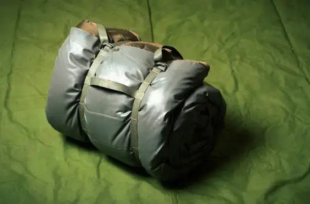 Military sleeping bag wrapped on army tent